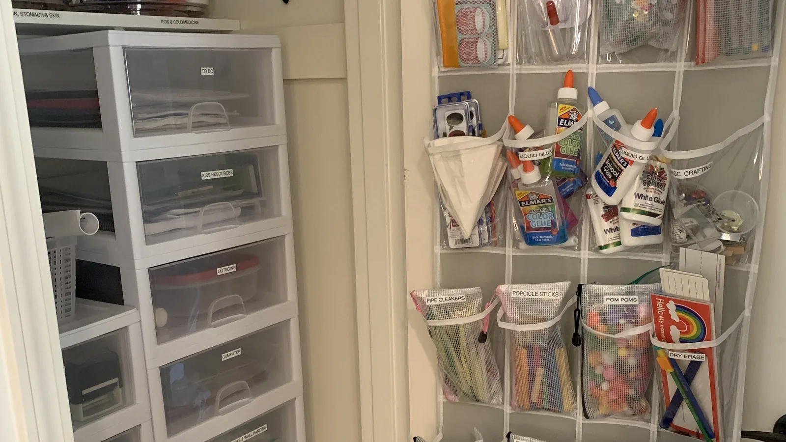 Labeled hanging pockets of craft supplies on a closet door next to stacked clear drawers.
