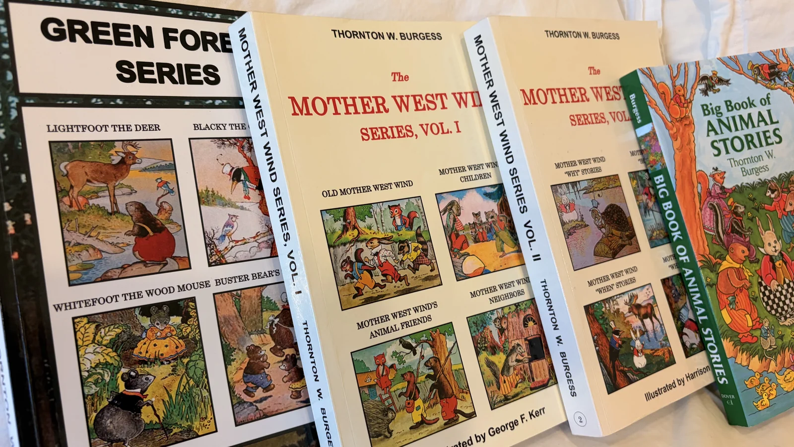 Stack of Thornton Burgess Mother West Wind and Green Forest books on a white cloth