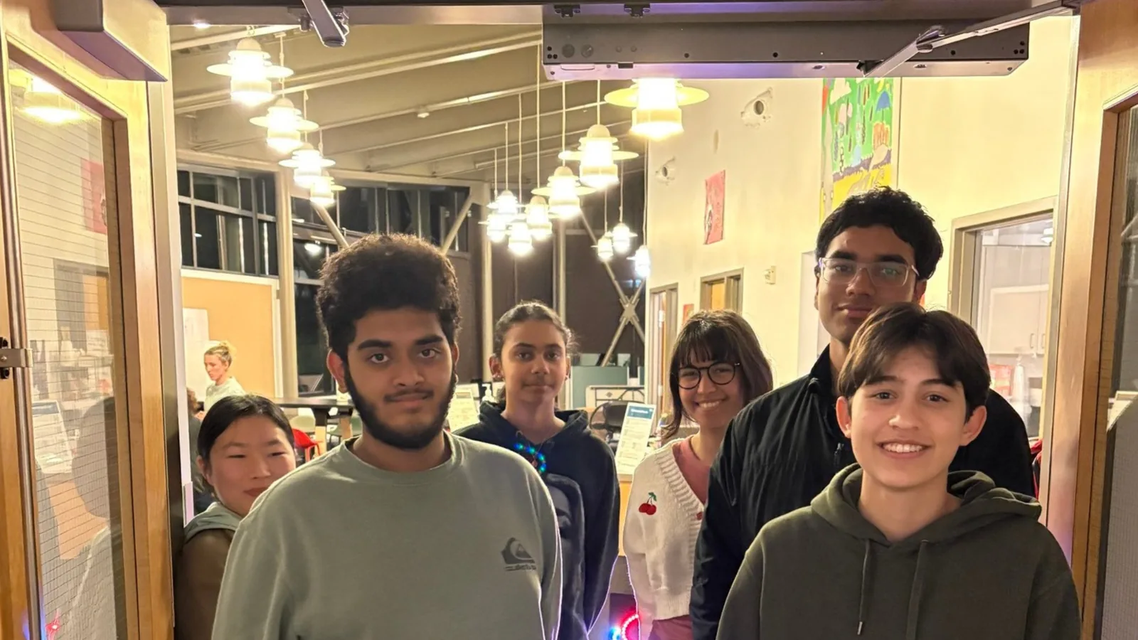 Teens in the Teen Lounge at Redmond Community Center at Marymoor Village, with a neon sign that reads Teen Lounge.